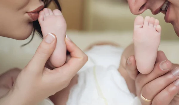 Amor y cuidado. Estilo de vida familiar. Una familia joven. Bebé recién nacido piernas y padres beso . — Foto de Stock