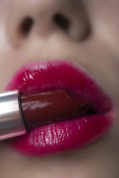 Air kiss. Close up cropped shot of femenine gorgeous charming adorable lady with amazing mouth, tube of hard pink lipstick pomade in mouth. Pampering, lips correction concept. — Stock Photo, Image