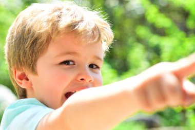 Genç gülümseyen çocuk mutlu bir şey işaret. Neşeli çocuk sometinhg buldu. Genç erkek mutlu duygular scincere. Aile açık yaz günleri. Yeşil renkli arka plan