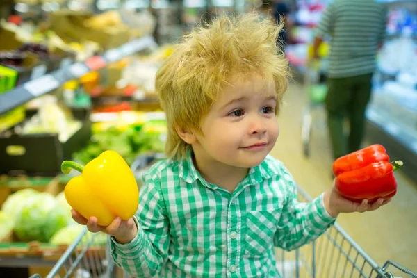 コショウと面白い子供。夕食に野菜を健康的な食事。赤または黄コショウ。スーパーマーケットでの食べ物の選択。野菜の値段。販売と割引。バイオ食品。エコロジー製品 — ストック写真