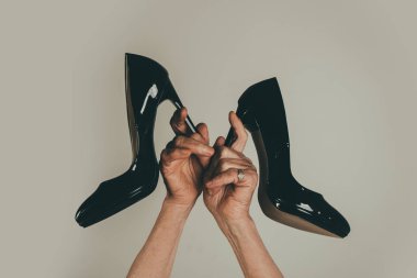 Ebedi moda. Eski kadın elleri siyah yüksek topuklu çifti tutarak yakın. Yaşlı bayanlar için rahatsız ayakkabılar. Varis ve yaş ile ilgili hastalıklar. Rahatsızlık ve moda. Eski Prenses