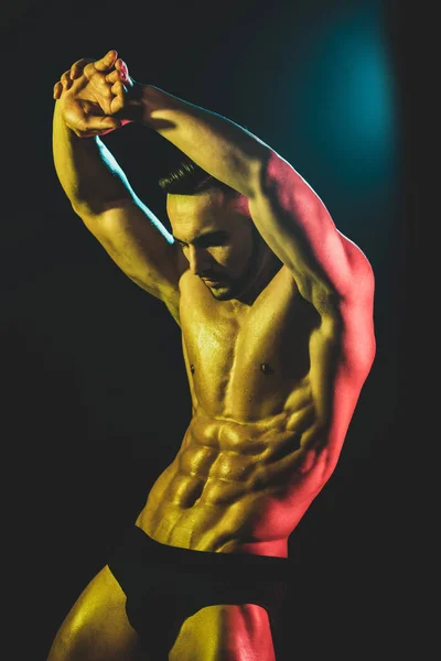 Μυώδης μοντέλο Αθλητισμός νέος άνθρωπος σε σκοτεινό φόντο. Μόδα πορτρέτο του ισχυρού βάναυσο άντρα με ένα σύγχρονο μοντέρνο χτένισμα. Σέξι κορμός. ' Ντρας που τεντώνει τους μυς του. Αθλητισμός προπόνηση bodybuilding ιδέα. — Φωτογραφία Αρχείου