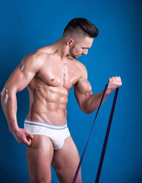 Fitness belt, man sports with belt, sports equipment, tools for training in gym. Handsome young man with strong body and beautiful muscles. Naked man in white shorts gym. Athletics, Personal Trainer