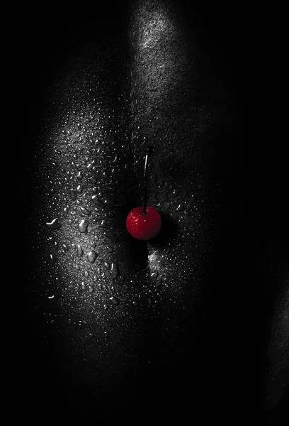 Red cherry on a black body. Sexy African-American woman. Seductive and attractive dark skin. Black and white photo. Passion and temptation, sex with a woman. Beautiful body after training, fitness — Stock Photo, Image