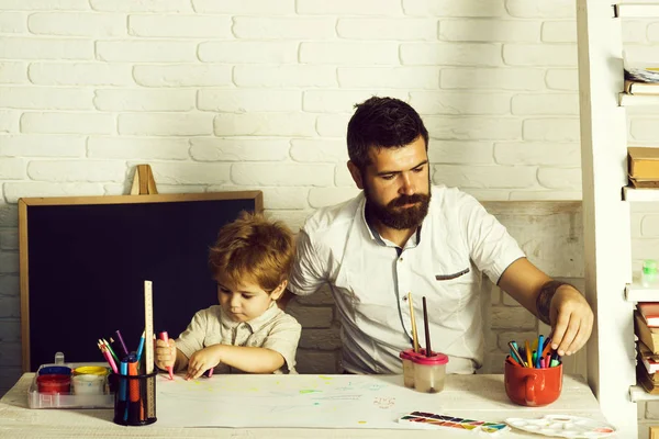 Thuisschool. Team werktekening, vader en zoon schilderen samen, vader leert zijn zoon hoe te schilderen correct en mooi op papier. Familie creativiteit en onderwijs thuis — Stockfoto