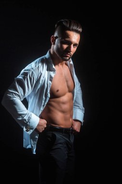 Çekici ciddi adam. Siyah arka plana karşı çıplak göğsü ile beyaz gömlek seksi adam. Sakallı adam spor vücudunu gösteriyor, ABS. Mens giyim. Erkek moda. Şık genç sakallı adam