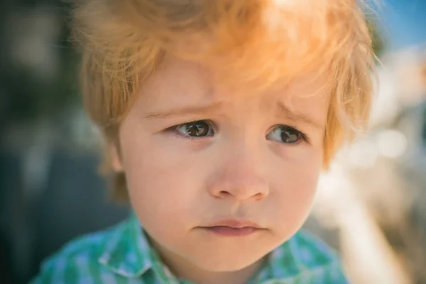 Frustration, child emotions. A sad child looks into the distance. Beautiful face. Cute boy. Sadness and tears, disappointment, childhood experiences. Face close-up portrait, children