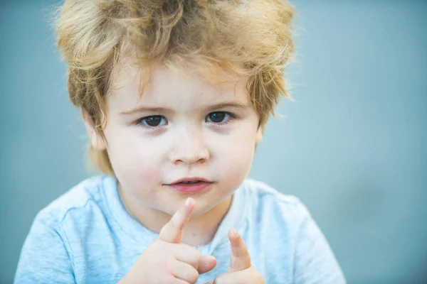 Gyermek ujjaival felmutat. Gyönyörű baba arca. Gyermek portré. Szőke preschooler. Okos gyerek keresi a kamerát. — Stock Fotó