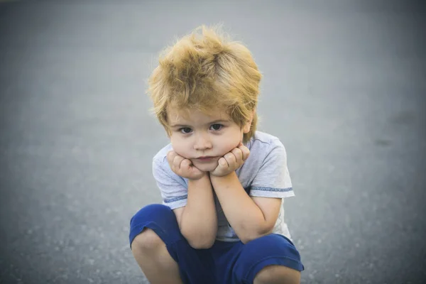 Triste chico mirando a la cámara. Niño solo. Un niño triste sentado en la calle. Niña infeliz. Piensa en una nueva idea . —  Fotos de Stock