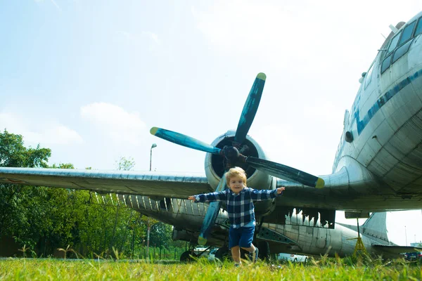 Avión y niño. El chico está huyendo de un gran avión en Green Glade. Emociones divertidas y felices de un niño pequeño después de ver aviones. Caminata familiar. Fondo de viaje Sty y aire fresco. Ejercicios de ejecución —  Fotos de Stock