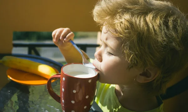 Du lait savoureux. L'enfant mange le petit déjeuner. Aliments sains pour les enfants. Petit déjeuner en plein air. Menu pour enfants d'âge préscolaire. Protéines, aliments riches en protéines. Bouillie de fruits et de lait . — Photo