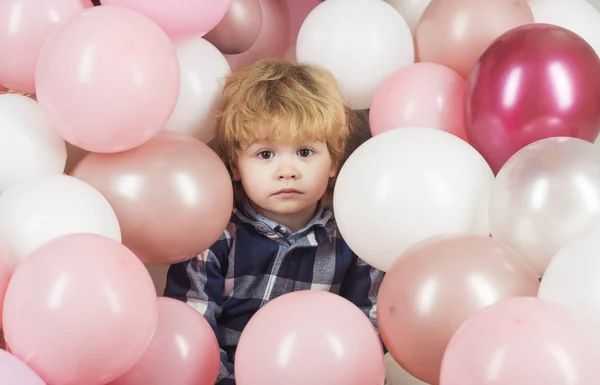 Удивлённые эмоции, удивлённый ребёнок смотрит на камеру на фоне розовых и белых шариков. Красивое детское лицо, портрет красивого ребенка. Привлекательный мальчик с большими глазами. День рождения — стоковое фото