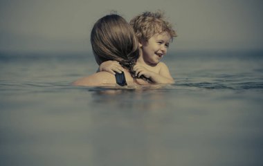 Yaz havası. Merhaba August. Denizde tatil. İnsanlar suyla çevrili. Oğluyla suda titriyor. Çocuklarla aile aktiviteleri. Denize yakın aile yaz tatilleri. Anne ile zaman, ebeveyn sevgisi