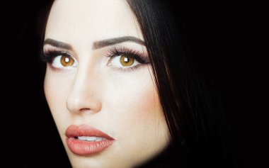 Güzel bir yüz. Kadın portresi. Esmer kadın. Güzel gözler. Kahverengi gözler. Makyajlı kız yüzü. Koyu saç boyası ve yüz bakımı.