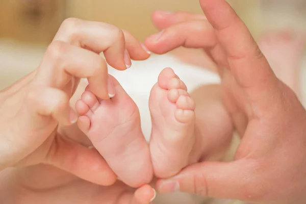 Bébé jambes coeur. Parents tenant dans les mains les pieds du nouveau-né . — Photo