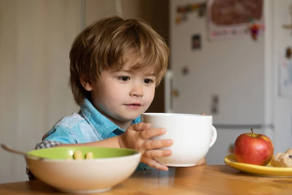Еда для детей. Мальчик на кухне. Ребенок с обедом дома. Детское питание. Фруктовые закуски . — стоковое фото