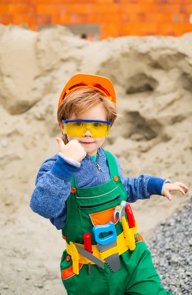 Builder thumb up. The boy is dressed as a builder. Future profession. Career guidance. Happy successful builder. Career. Business in the construction industry. The property. Child game.
