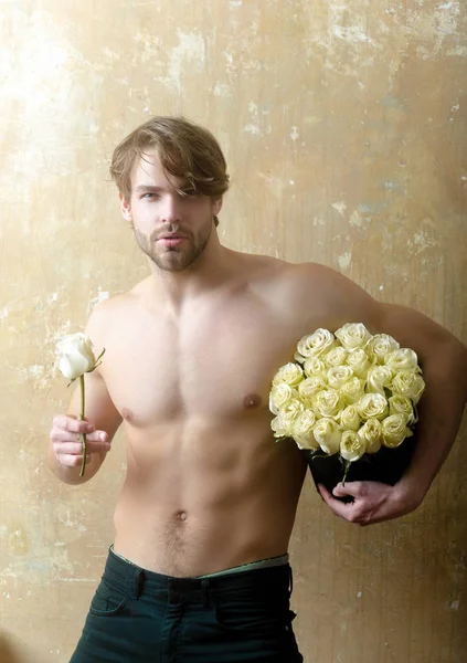 Handsome man with bouquet of white roses. Great present for girlfriend. Flowers and loved ones attention for her. Charms of love. Valentines Day gift. Spring and date. Sex relations with naked man