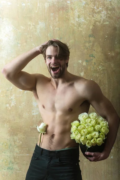 Feliz hombre sexy con flor blanca. Lindo macho sosteniendo rosas de flores. Feliz marido romántico sosteniendo flor de rosa y preparado para celebrar. Amor fondo masculino — Foto de Stock