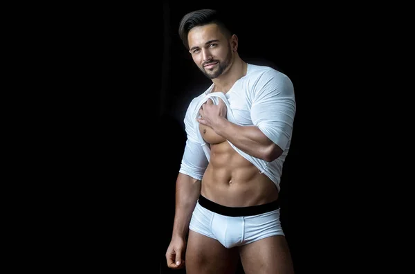 Abs. Sexy man shows body, torso and press, bare chest. Attractive guy in white T-shirt. Handsome guy, morning dress underwear. Seductive man, sport body. Bearded stylish young man on black background — 图库照片