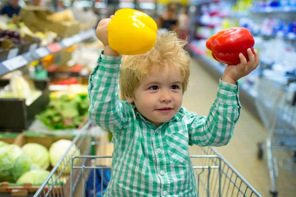 子供と野菜健康的な食べ物。その少年は赤と黄色のピーマンを手に持っている。スーパー マーケット. — ストック写真