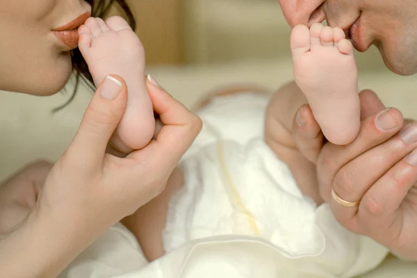 Mère et père. L'amour familial. Un nouveau-né. Les parents embrassent bébé pieds . — Photo