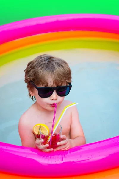 Summer cocktail. Vacation. Summer holidays. The child drinks colorful cocktail in sunglasses. Enjoyment Resort. Cocktail pool for relaxing. Happy time. Happy hours. Luxury life. Delicious heat drink.