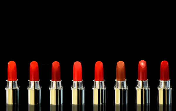 Shot of red lipsticks of different color. Isolated on black background. Cosmetics concept. Beautiful Luxury Modern High End Red Bold Lipstick. Beautiful dark red lipstick for cosmetics advertising.