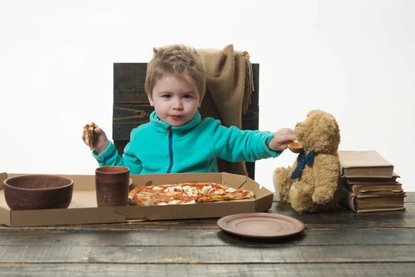 供給。その少年はおもちゃのクマに餌をやる。自宅でピザとイタリアのパーティー. — ストック写真