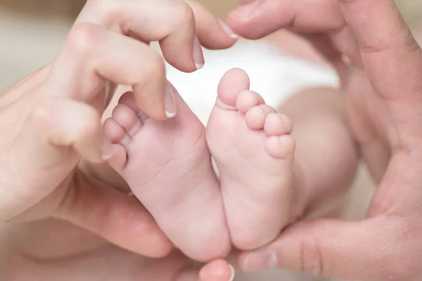 Gros plan des pieds du nouveau-né. Pieds de bébé entre les mains de la mère. En forme de foyer familial. Amour et soins. Maman et papa aiment . — Photo