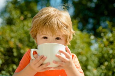 Cute child drinks milk. Healthy food and drink for children. Summer drinks. Baby boy and hot summer holidays. clipart