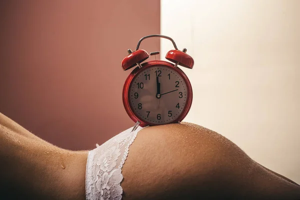 Word wakker. Ochtend wekker op de naakte vrouwelijke kont. Tijd en de droom. Veroudering. Huid en billen. Vrouw en tijd concept. — Stockfoto