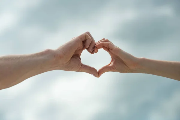 Kalp işareti. Eller gökyüzü arka planda bir kalp sembolü gösterir. Aşk. Erkek ve kadın. Ortaklık. Cinsiyet Eşitliği. Kadın ve erkek arasındaki aşk. — Stok fotoğraf