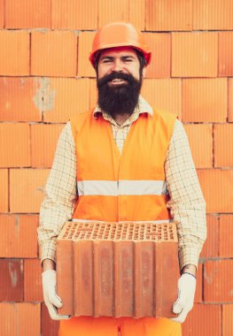 Turuncu duvar inşaat arka plan üzerinde tuğla ile Adam. Şantiyede inşaat inşaatçı sı.