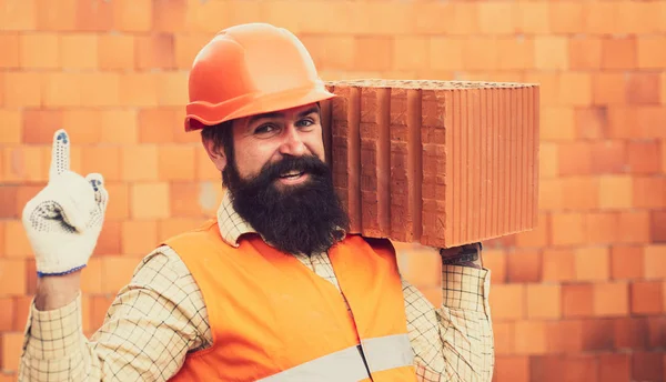 Builder tamirci işçisinin parmak noktası ile el. Koruyucu yelek ve kask giymiş inşaatçı. Şantiyede çalışan biri. Turuncu tuğla.