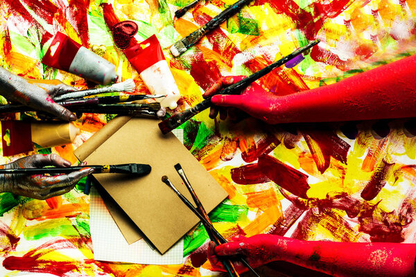 Empty page on colorful background. Plastic hands and brightness of color. An unusual combination. Fantastic picture. Flexible fingers hold thin tassels. Artists in the creative process