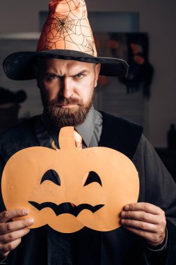 Balkabağı ile Cadılar Bayramı kostümü. Büyücü kostümü giymiş sakallı, çekici bir adam. Cadılar Bayramı partisinde alet. Seksi büyü. Sihirbazlar kapağı.