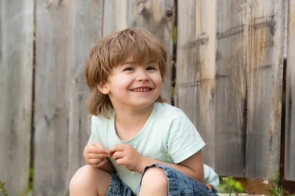 Feliz niña. Un chico se sienta cerca de una cerca de madera. Preescolar y Otoño. Pensamientos felices . —  Fotos de Stock