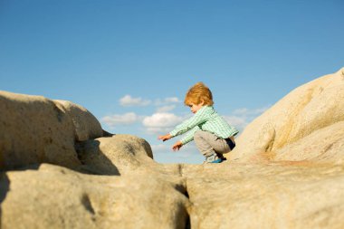 Atlamak. Kayaların üstündeki atlayıcılar. Eğlence. Doğada çocuk. Denize yakın Yunan taşları. Eğlenceli.