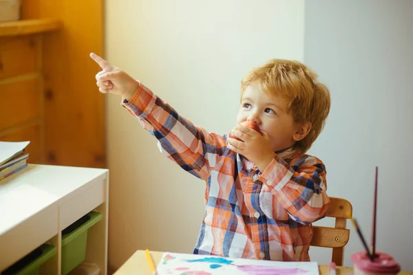 A gyermek eszik egy almát, és játszik. Egészséges snack. Gyönyörű fiú. Ebéd otthon. — Stock Fotó