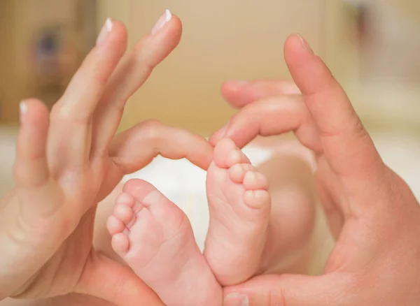 Pieds nouveau-nés sur les mains féminines, en forme de coeur charmant. Pieds de bébé entre les mains des parents. Amour de famille . — Photo