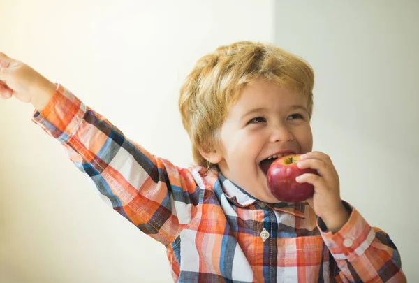 Мальчик ест яблоко. Красивый эмоциональный ребенок ест фрукты и улыбается. Вкусная здоровая еда и счастье дома. Продуктовый магазин, ферма, яблоневый сад, яблочная реклама . — стоковое фото