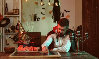 Cadılar Bayramı oyunu. Baba ve oğul birlikte Cadılar Bayramı süslemeleri yapmak. Bir tahta üzerinde tebeşir ile çizin. Ev partisi. Sonbahar akşamı.