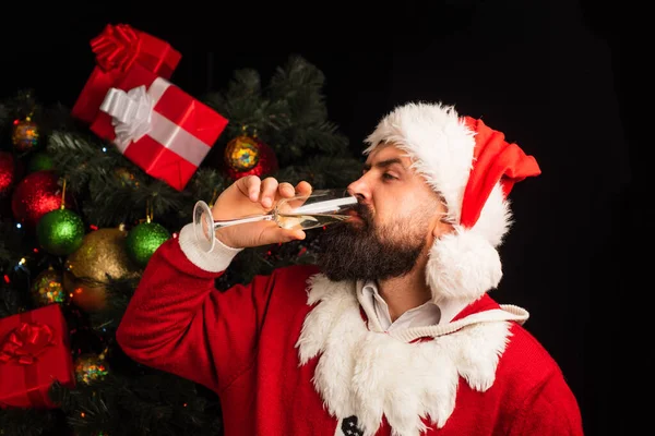 Alkohol på helgerna. Grattis på julfesten. En man i jultomte dricker vin ur ett glas.. — Stockfoto