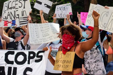 Miami Downtown, FL, USA - MAY 31, 2020: Police and Breonna Taylor poster. Woman on peaceful protests in the US against the George Floyd death: people are protesting. Female activist protestor. clipart