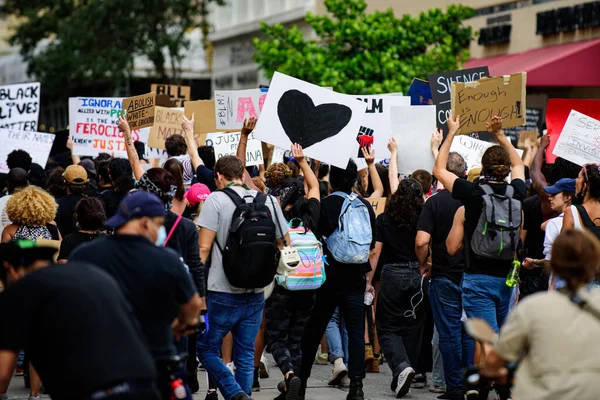 Miami Downtown, FL, USA - Június 12, 2020: Black Lives Matter. Az USA utcáin emberek ezrei vesznek részt a rasszizmus elleni tüntetéseken. Fekete szív egy poszteren. Amerikai békés tüntetések a rasszizmus ellen. — Stock Fotó
