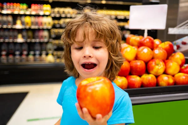 おいしいリンゴ。子供は食欲をそそる。子供が赤いジューシーなリンゴを噛もうとしている. — ストック写真