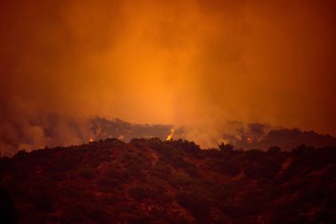 Kaliforniya dağlarının üzerinde turuncu gökyüzü. Los Angeles yakınlarında yangın çıkmış. ABD havasında duman kirliliği.