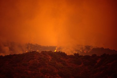 Kaliforniya dağlarının üzerinde turuncu gökyüzü. Los Angeles yakınlarında yangın çıkmış. ABD havasında duman kirliliği.