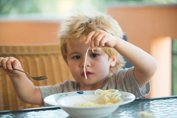 スパゲティ。おいしい食べ物、かわいい子供はスパゲティを食べる。テーブルの上のキッチンの子供はパスタを食べています。子供用イタリア料理. — ストック写真